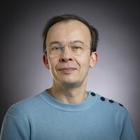 Un homme avec des lunettes et un pull bleu clair