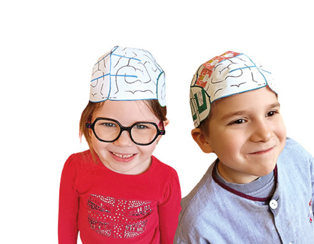 2 enfants souriants ont des sortes de maquettes de cerveau en papier sur leur tête.