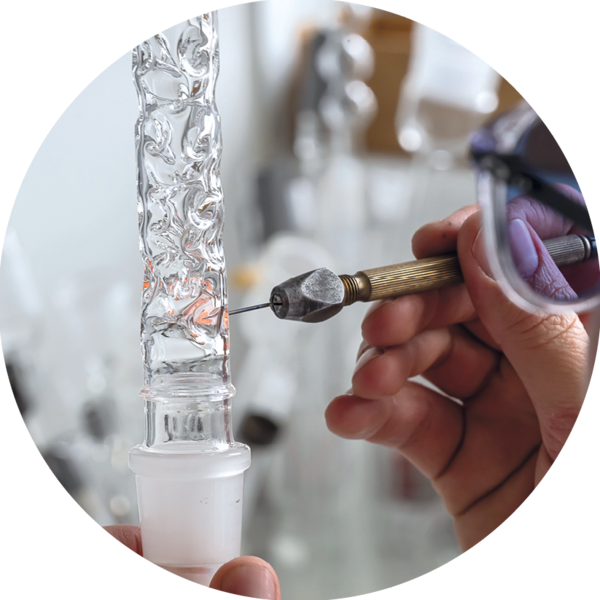 Une main introduit une pointe dans un tube en verre bosselé