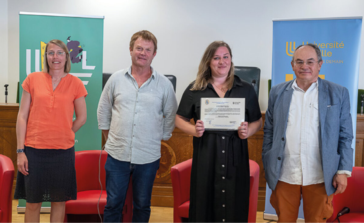 Deux hommes et deux femmes, dont une tient une affichette de prix. Derrière eux, des kakémonos