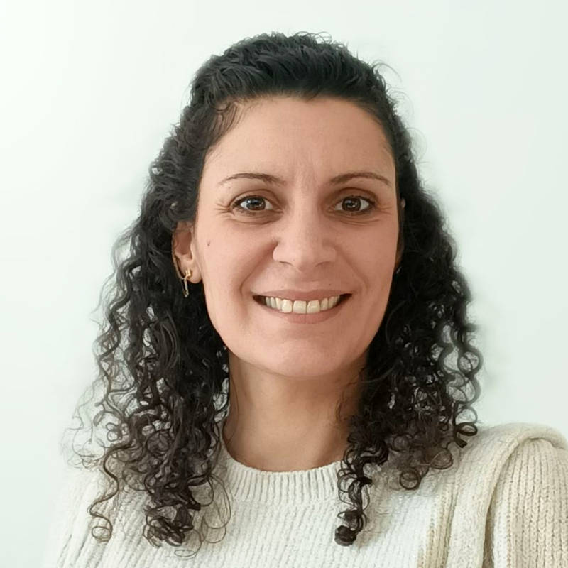 Visage d’une femme aux cheveux bruns et bouclés, avec un pull crème