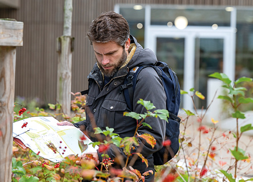 Un homme devant des plantes, consulte un document